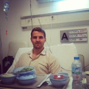 Danny sitting up in a hospital bed in Saigon, with a tray of food in front of him